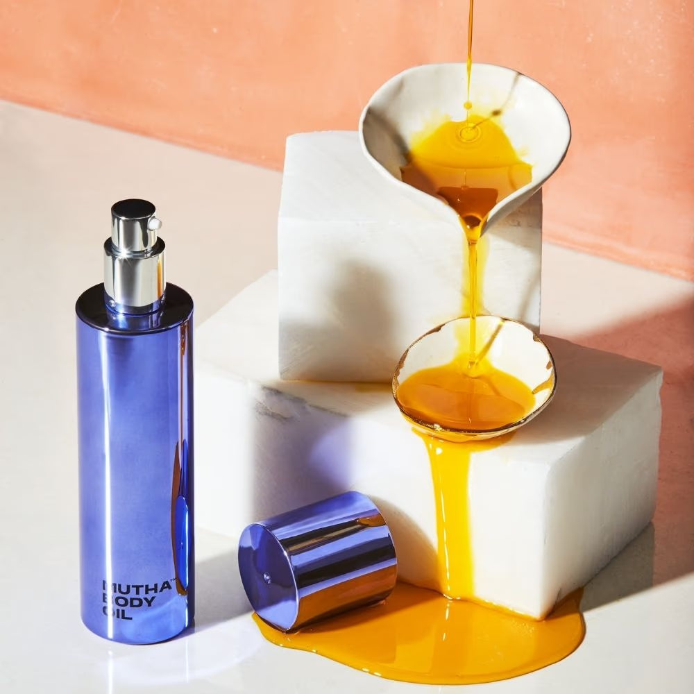 MUTHA Body Oil bottle with oil pouring over marble blocks.