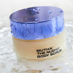 Jar of Mutha The Nudist Body Scrub with a purple lid on a textured white background