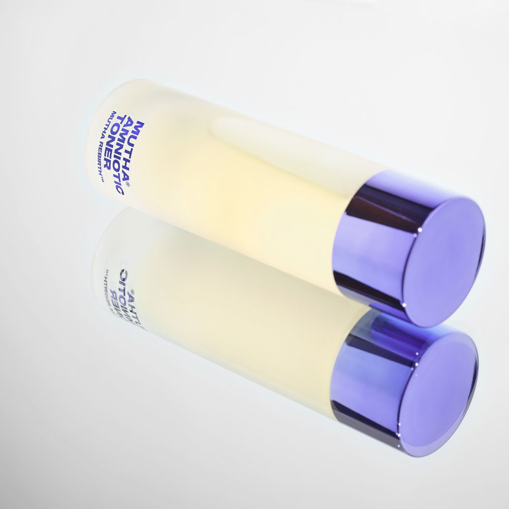 Amniotic Toner bottle lying on glass mirror with reflection