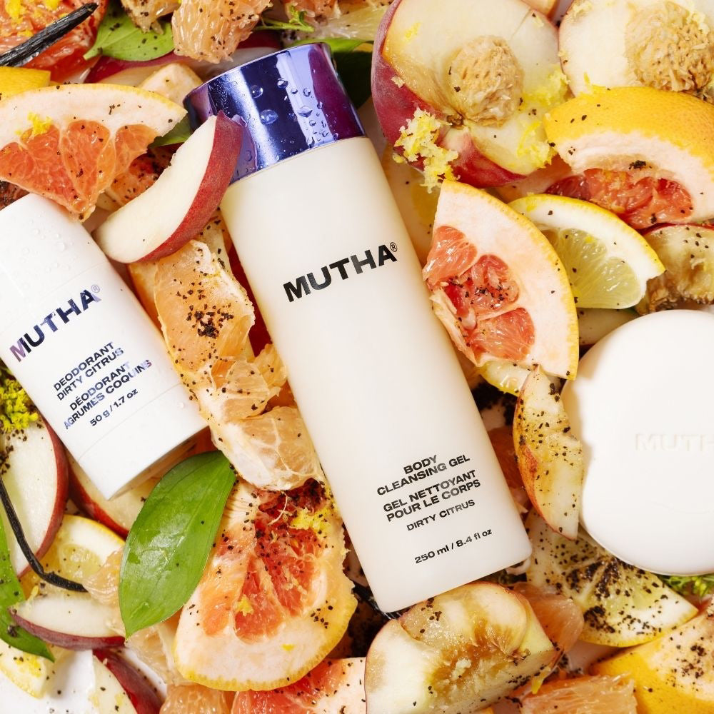 MUTHA body cleansing gel bottle surrounded by citrus fruits and vegetables