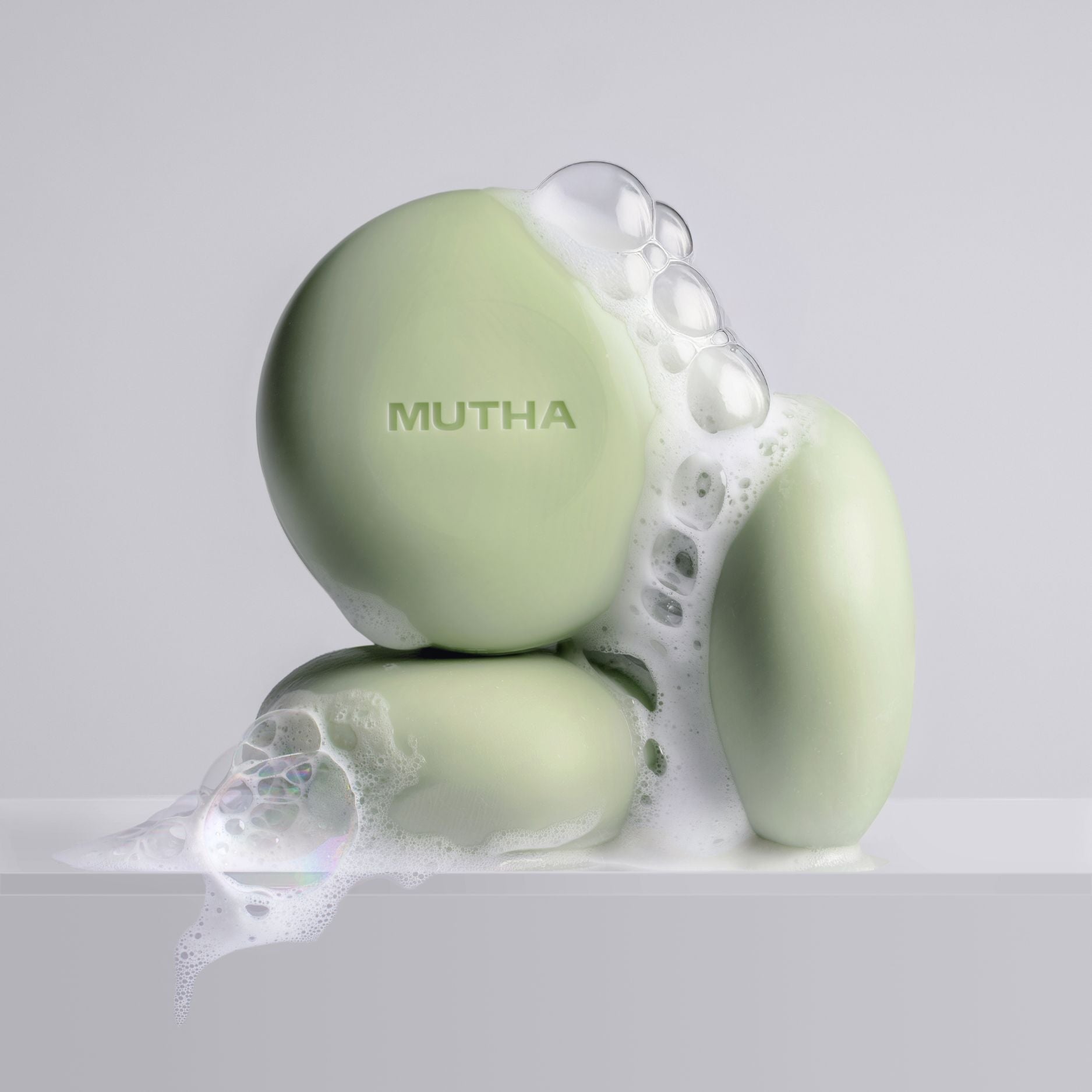 Green bath bombs with 'MUTHA' branding on a gray background