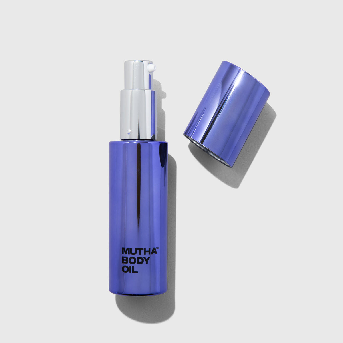 Mini MUTHA Body Oil bottle with the cap set beside it.