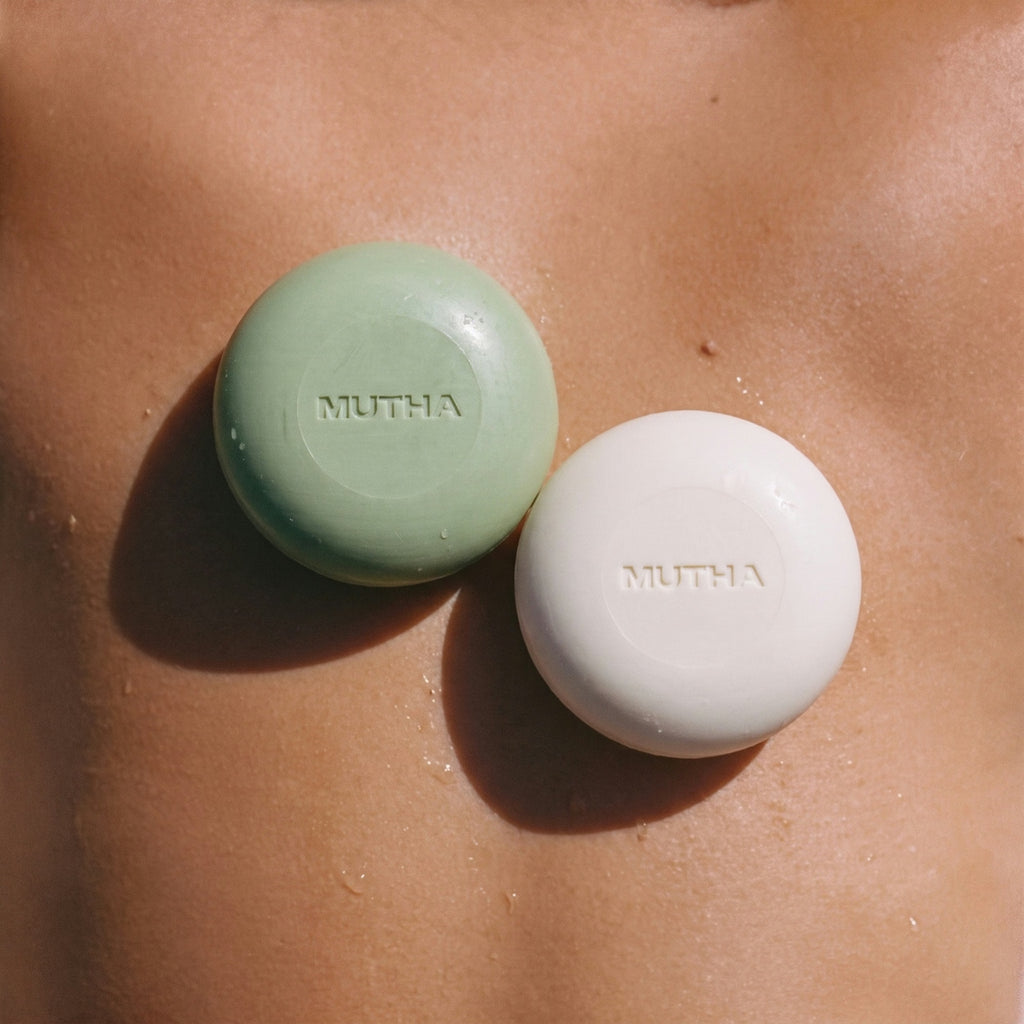 The Detox Greens and Dirty Citrus body bars resting on wet, sunlit skin