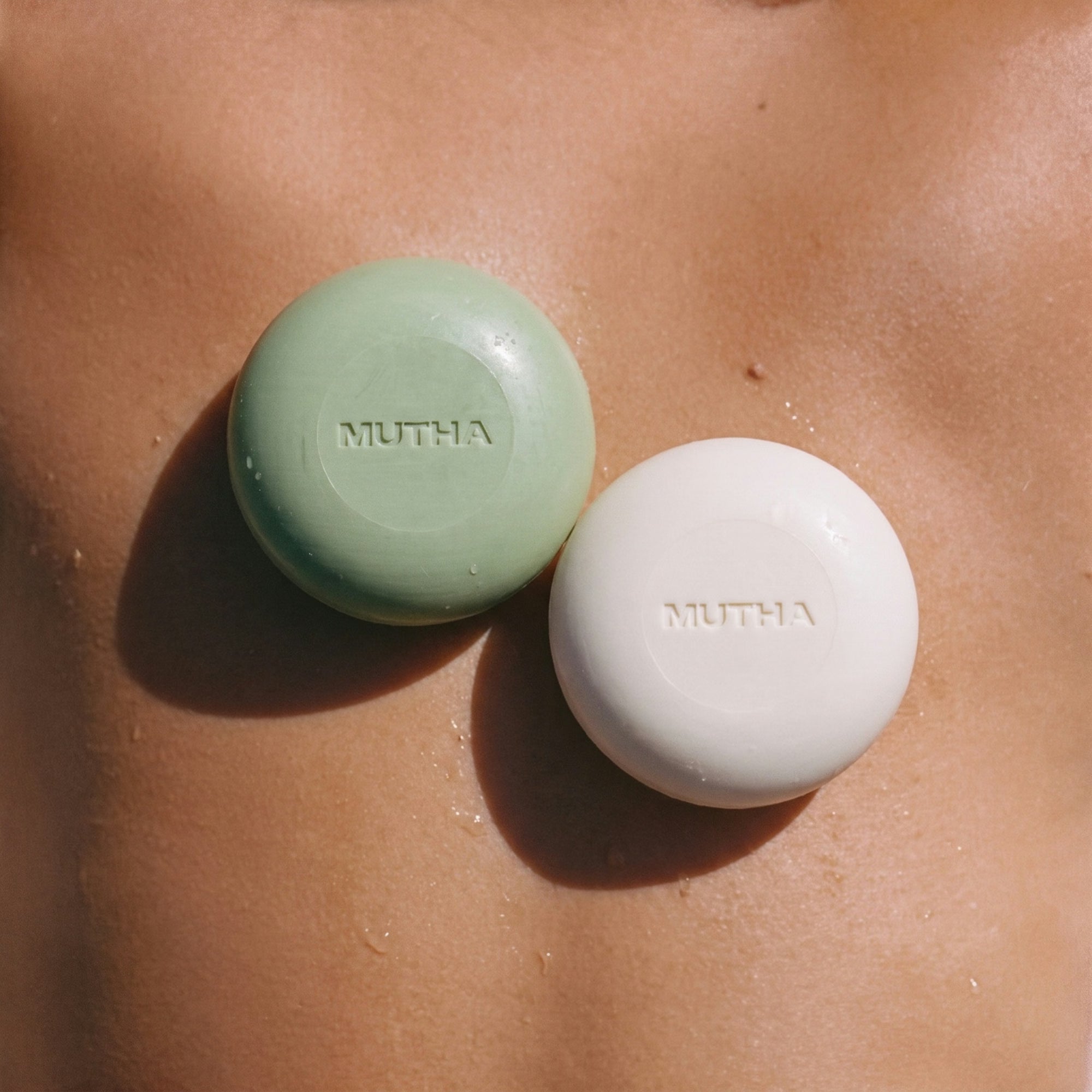 The Detox Greens and Dirty Citrus body bars resting on wet, sunlit skin