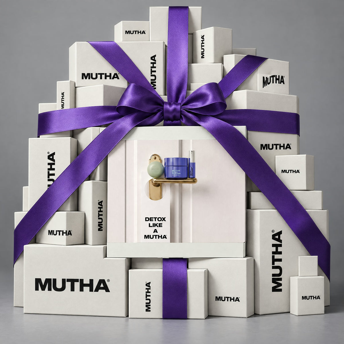 The Detox Like A MUTHA box at the centre of a stack of white MUTHA boxes tied with a wide purple ribbon.