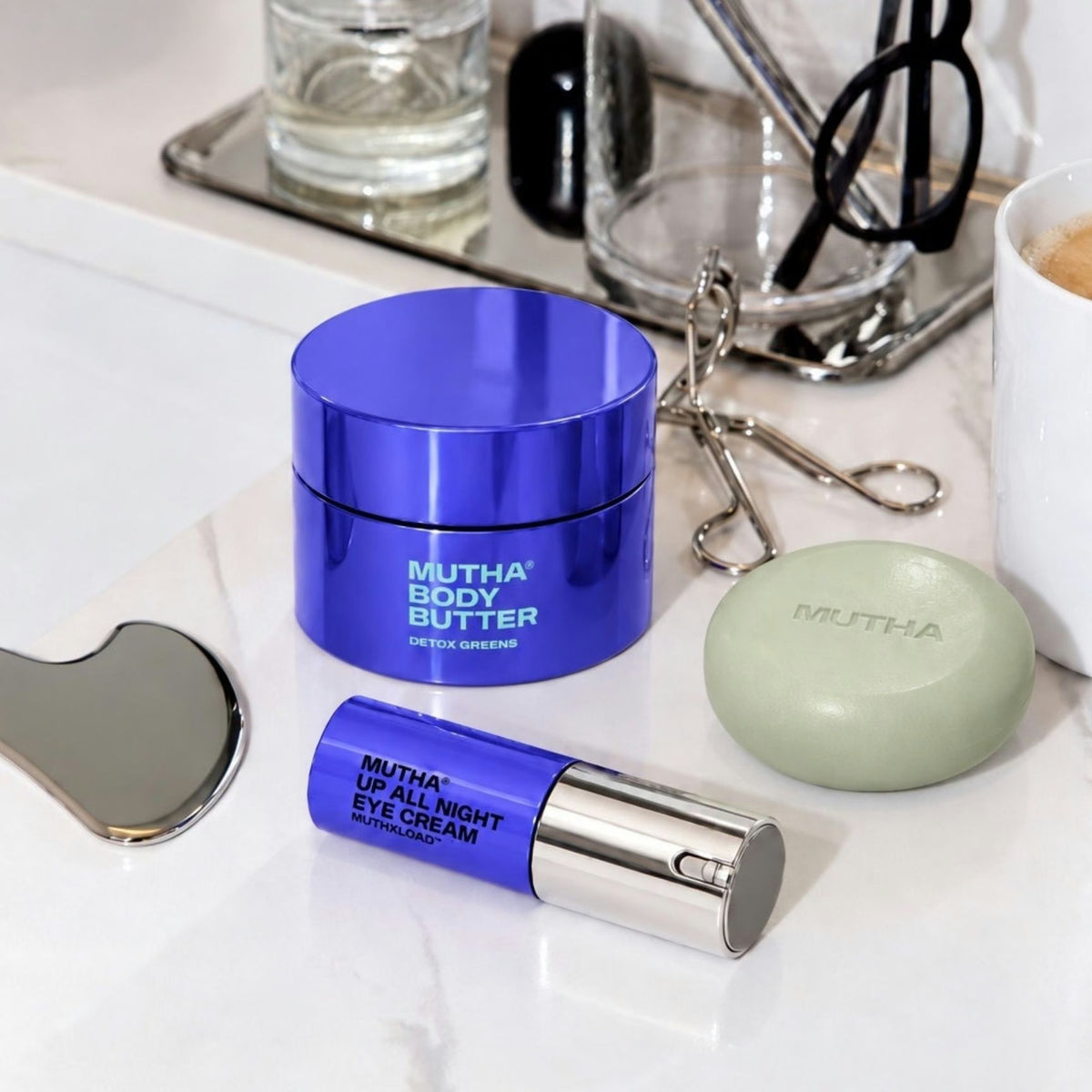 Detox Greens Body Butter, Body Bar and Up All Night Eye Cream on a marble vanity tray in morning light.