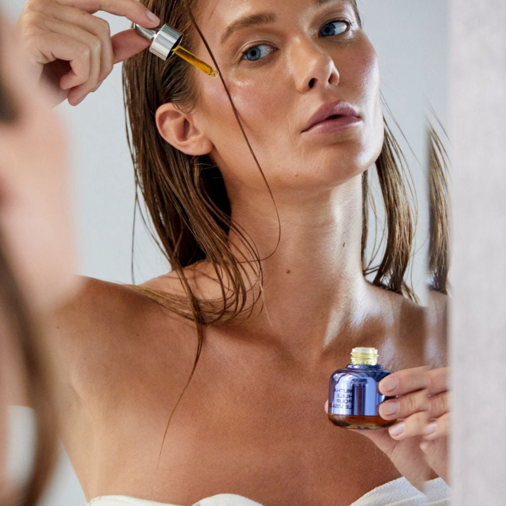 Model applying a dropper of MUTHA Face Oil to her cheek.