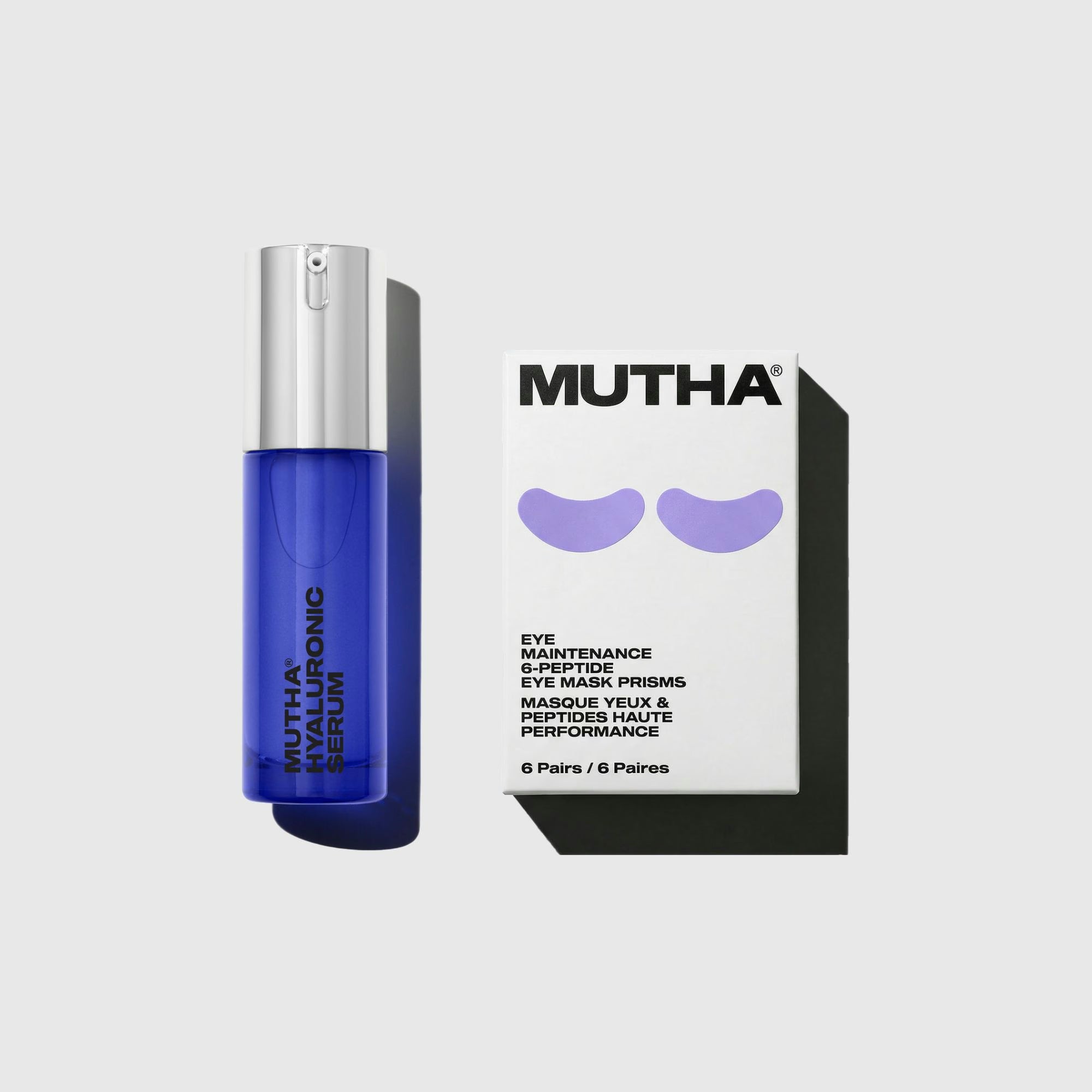 MUTHA Hyaluronic Serum in its cobalt blue bottle beside the Eye Maintenance 6-Peptide Eye Mask Prisms box on a pale grey background