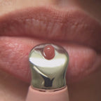 Macro footage of Pucker Up Lip Plump being applied with the metal applicator, leaving lips full and high-shine