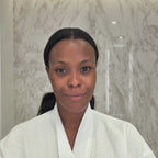 A model in a robe applies the purple Eye Mask Prisms under each eye in a marble bathroom