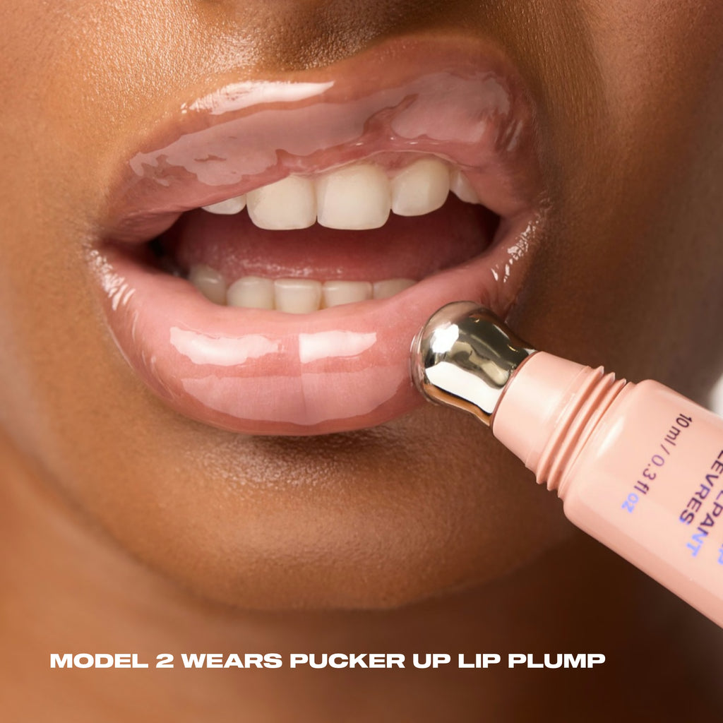 Close-up of a model applying Pucker Up Lip Plump with the metal applicator, showing the gloss's warm nude-brown shine