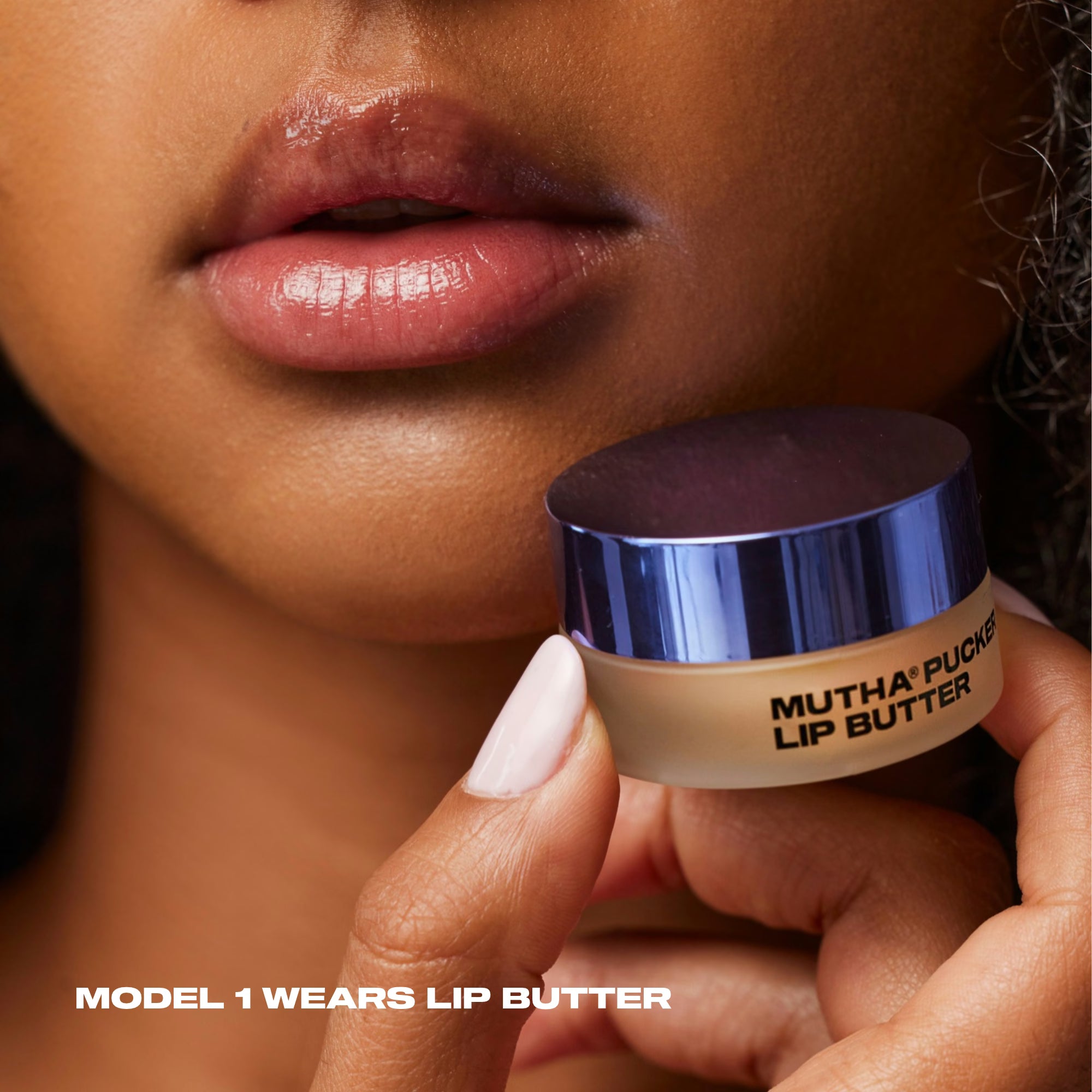 Close-up of a model wearing MUTHA Pucker Lip Butter, holding the jar beside softly glossy lips